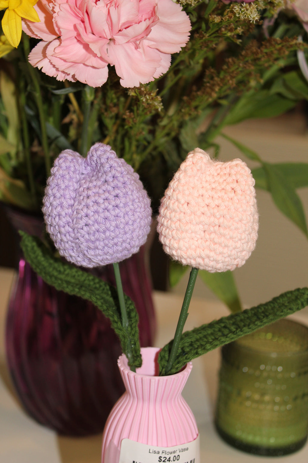 Decorative pink vase with 2 crochet tulips in it pink and purple. Close up view