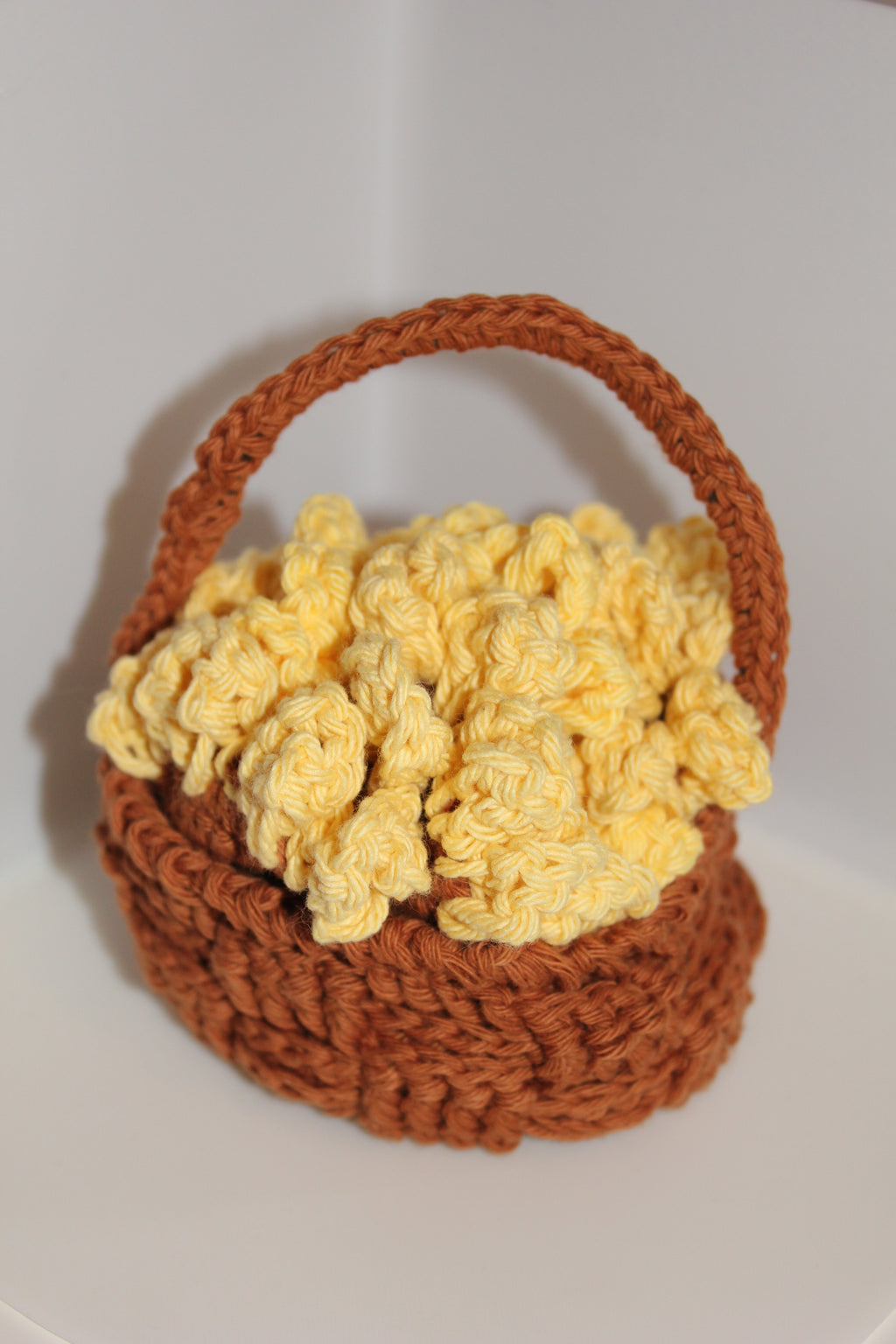 Crocheted brown basket with yellow sunflower coaster inside on a white background