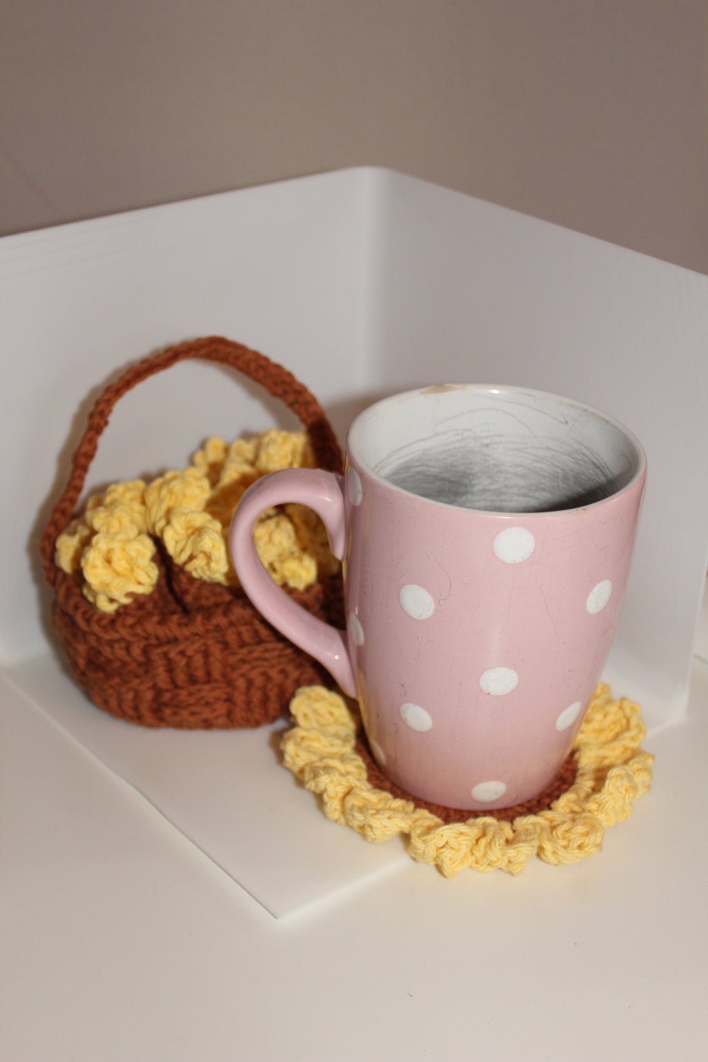 Pink mug on sunflower coaster with basket with coasters on the side