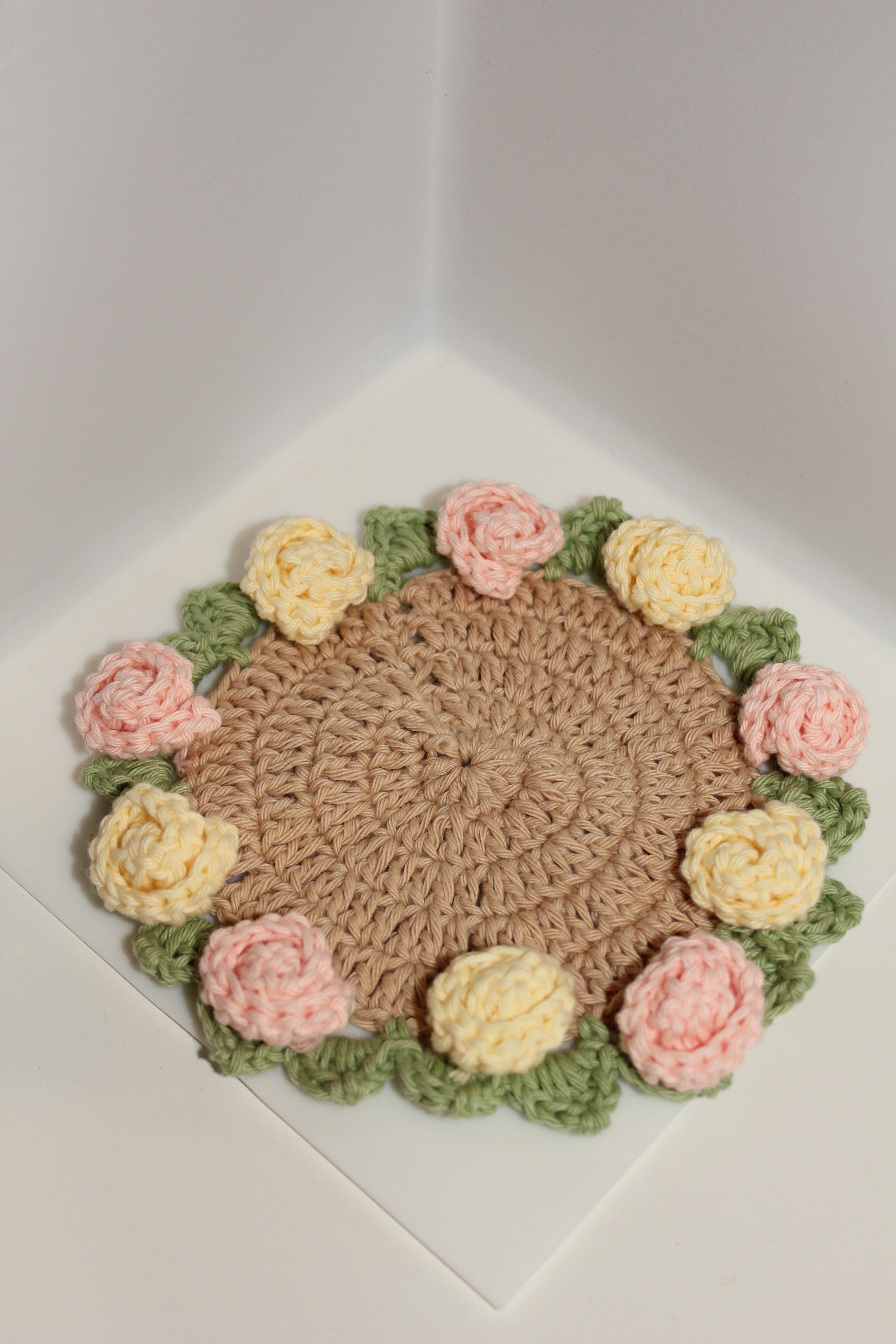 pink & yellow roses and green leaves coaster on a white background