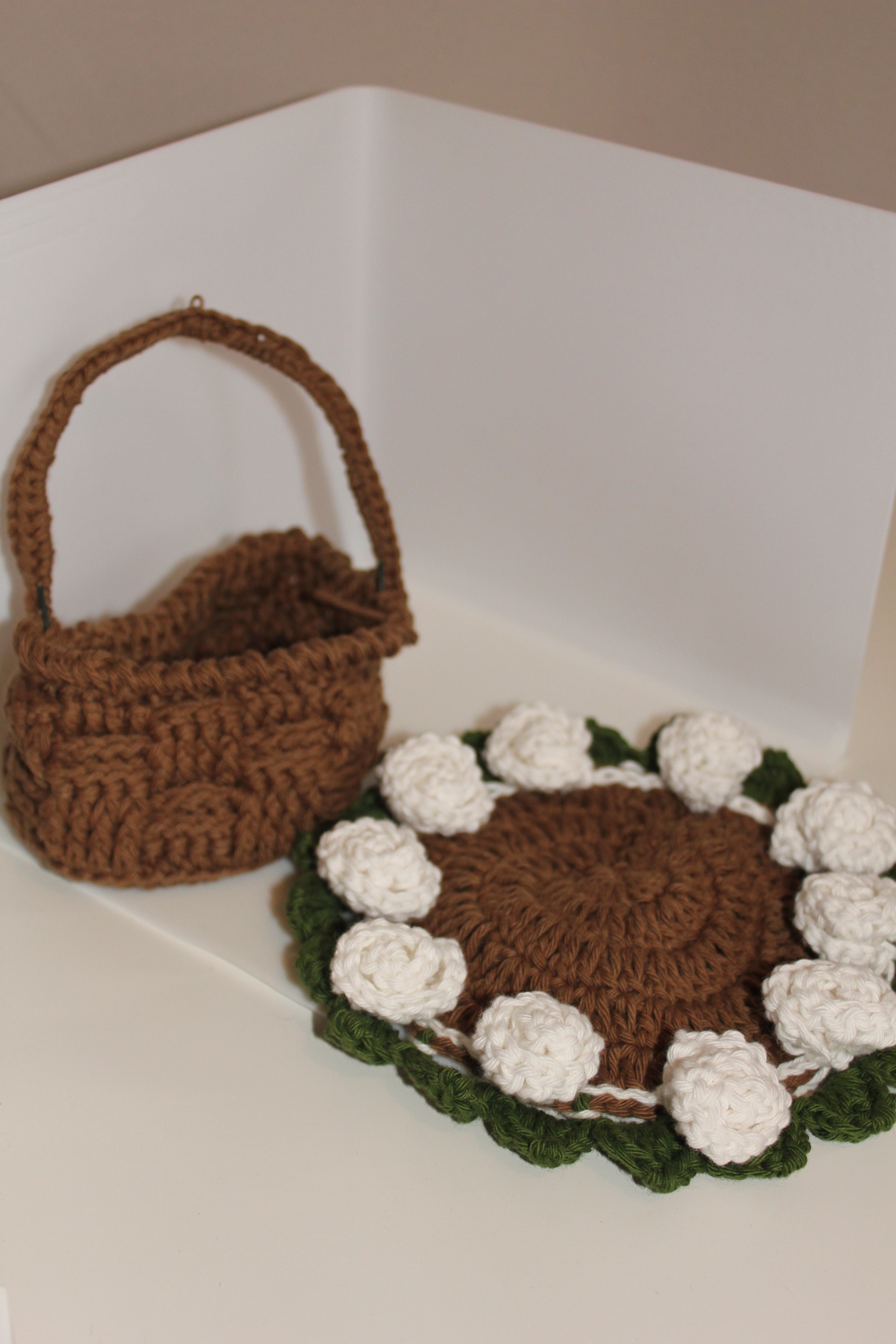 Crocheted brown basket with coaster on the side white roses green leaves 