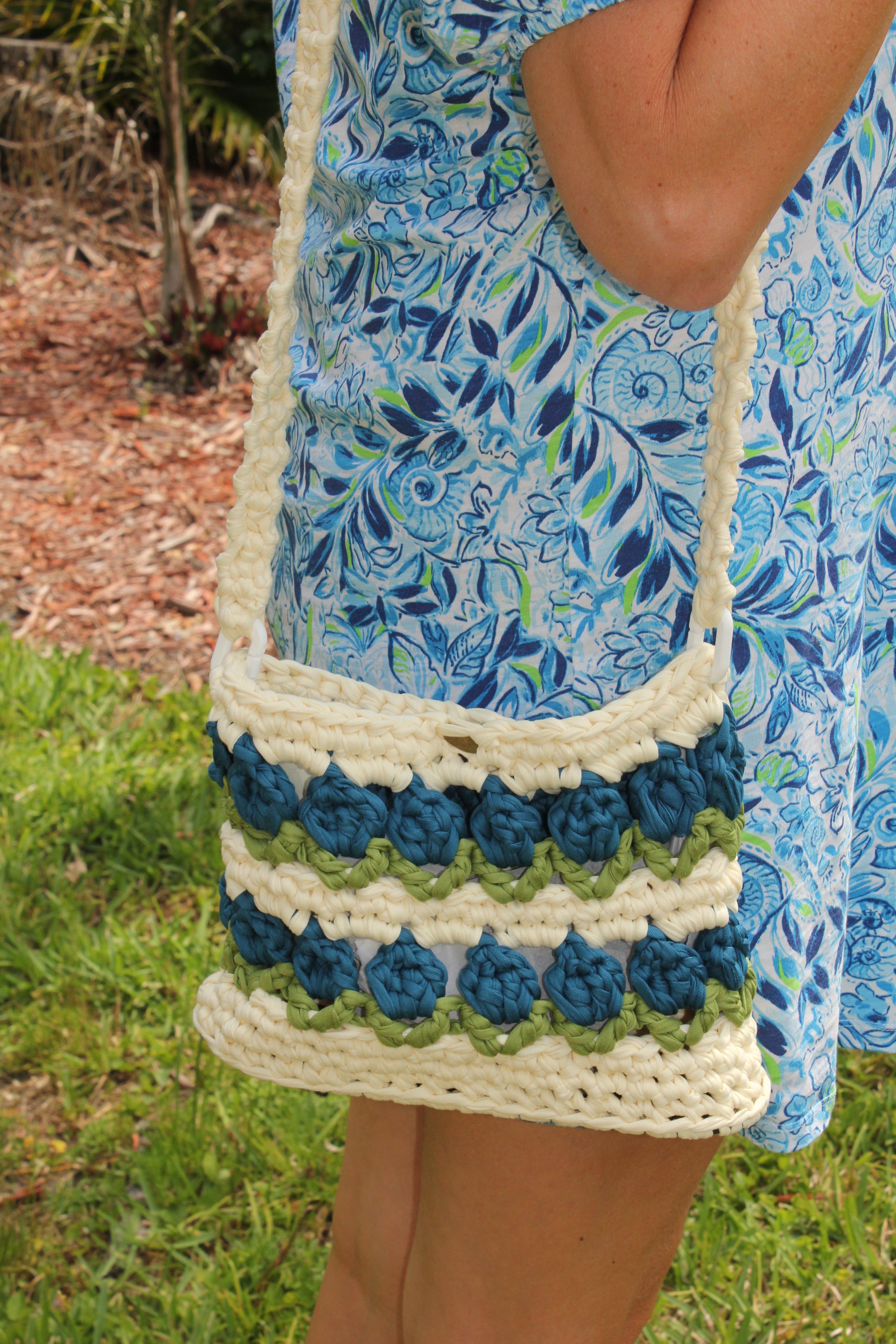 Crocheted tulip bag with blue and green flowers. Model side view