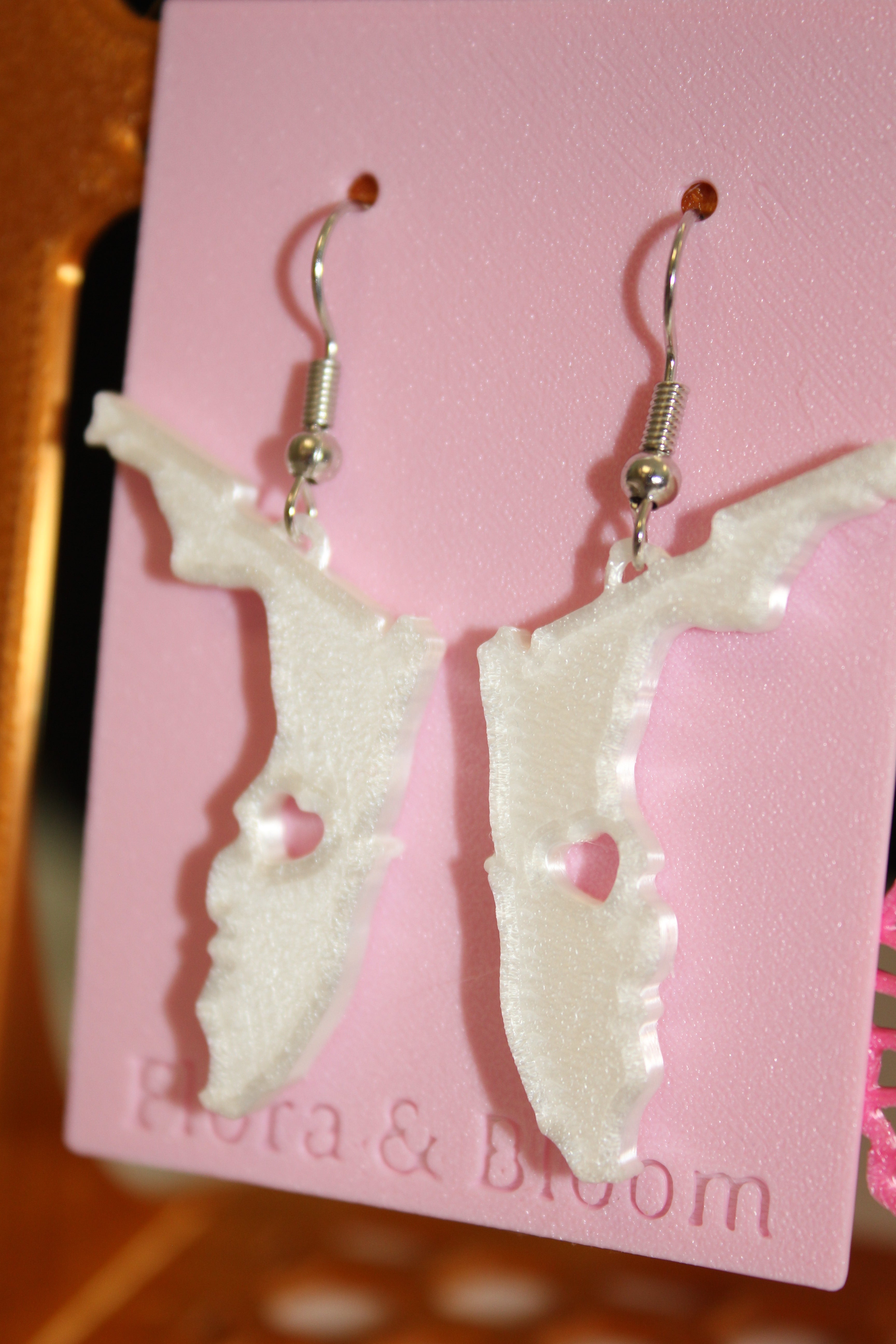 Florida shaped earrings on a pink 'Flora & Bloom' card. Side view