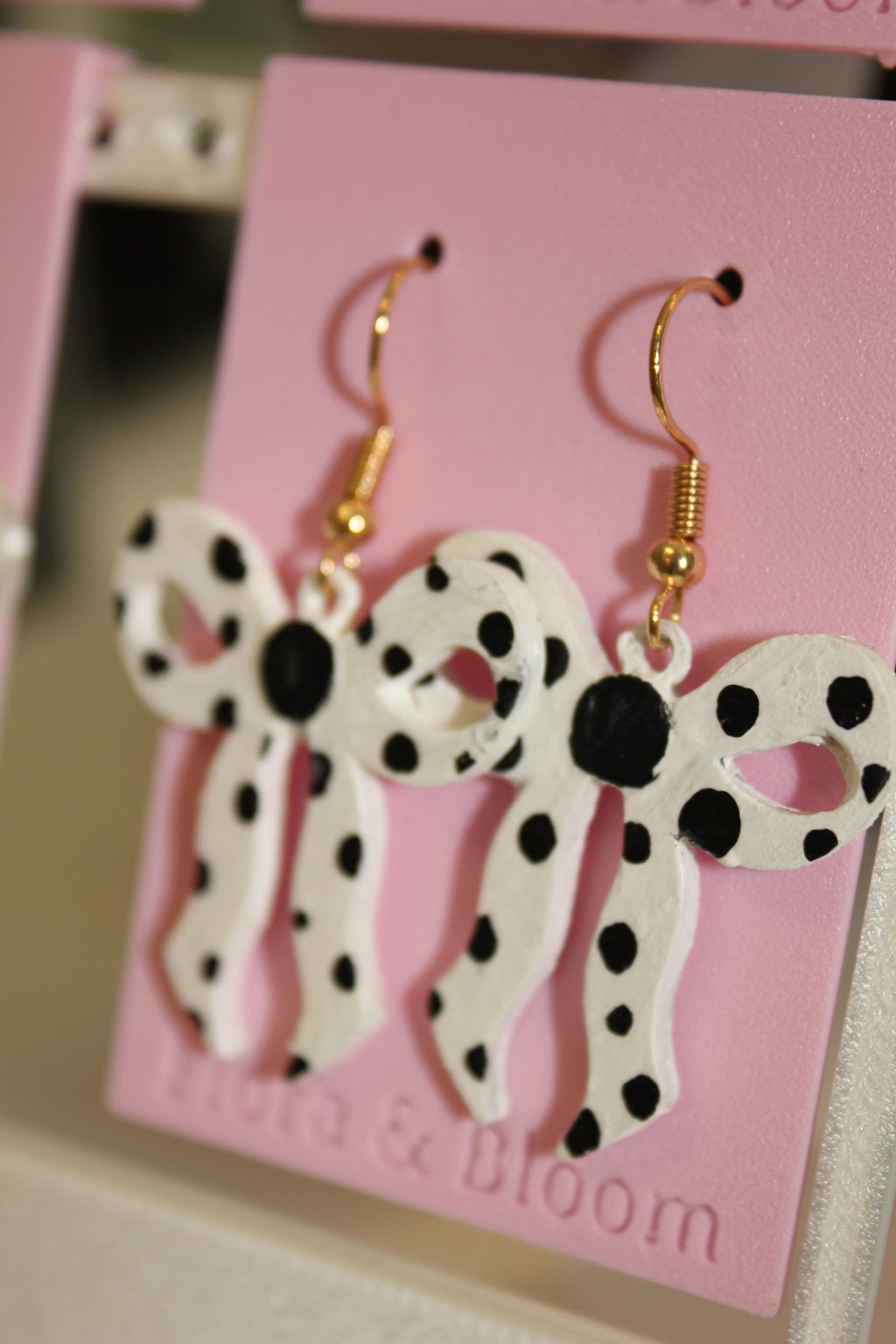 Painted polka dot earrings on a pink 'Flora & Bloom' card. Side view