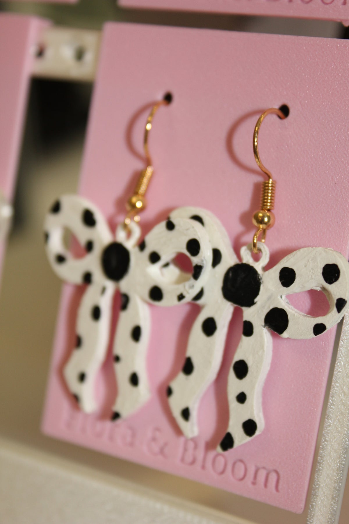 Painted polka dot earrings on a pink 'Flora & Bloom' card. Side view