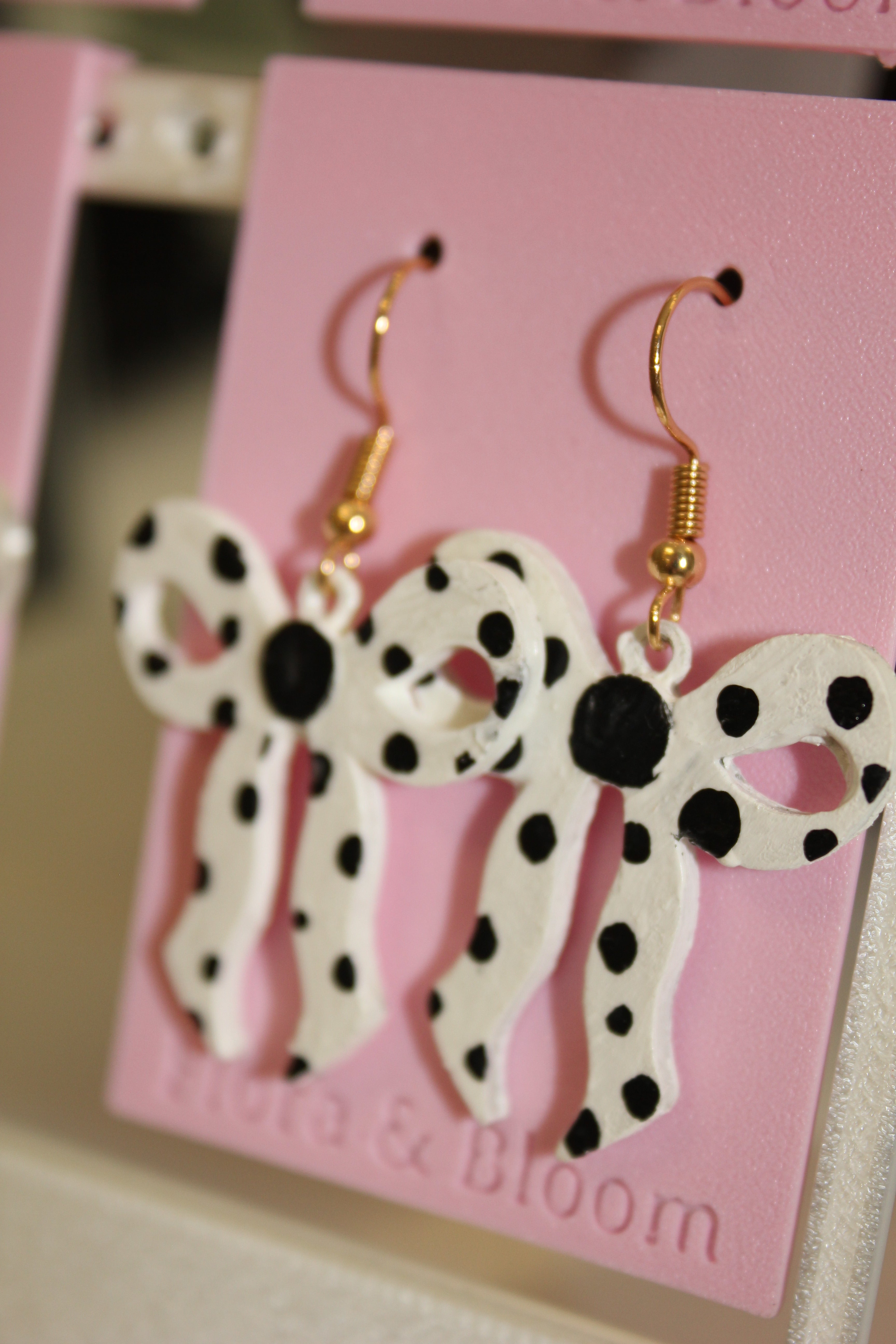 Painted polka dot earrings on a pink 'Flora & Bloom' card. Side view