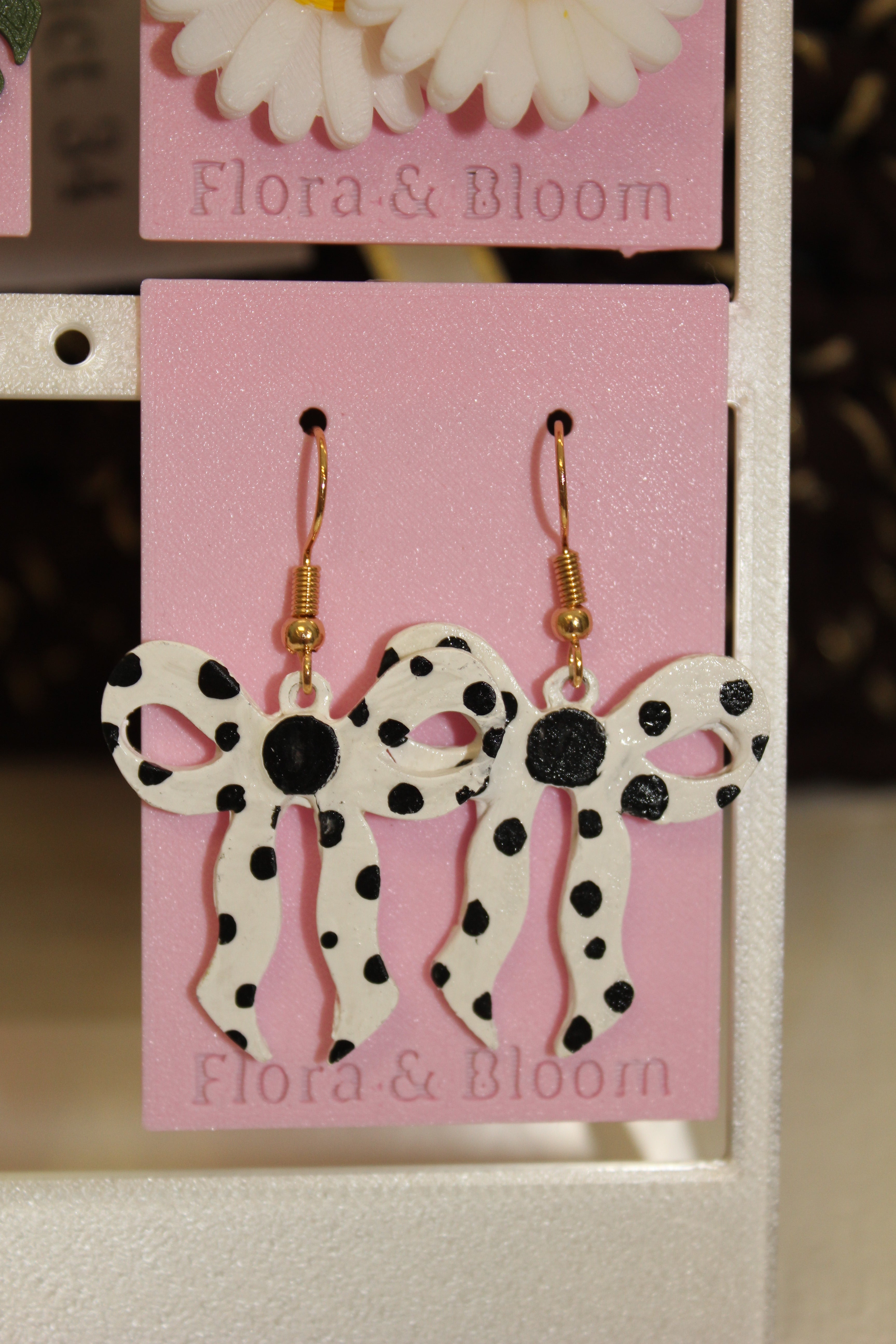 Painted polka dot earrings on a pink 'Flora & Bloom' card.